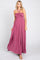 Woman wearing a mauve halter neck maxi dress with pleated bodice and flowy skirt on a white background