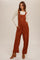 woman wearing rust-colored corduroy overalls with wide legs and side pockets, paired with a cream long sleeve top and brown ankle boots