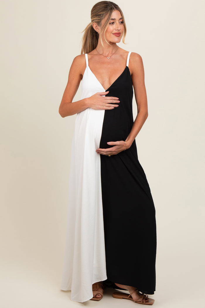 woman wearing a black and white maternity maxi dress, cradling her baby bump with one hand