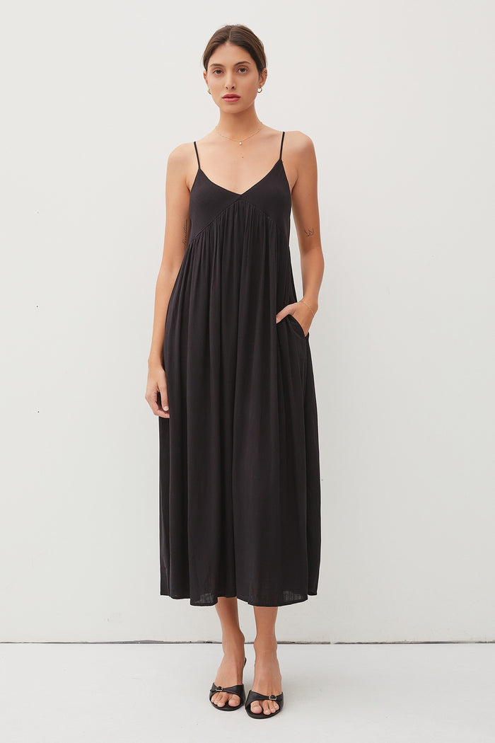 woman wearing a black sleeveless maxi dress with pockets and a flowy silhouette