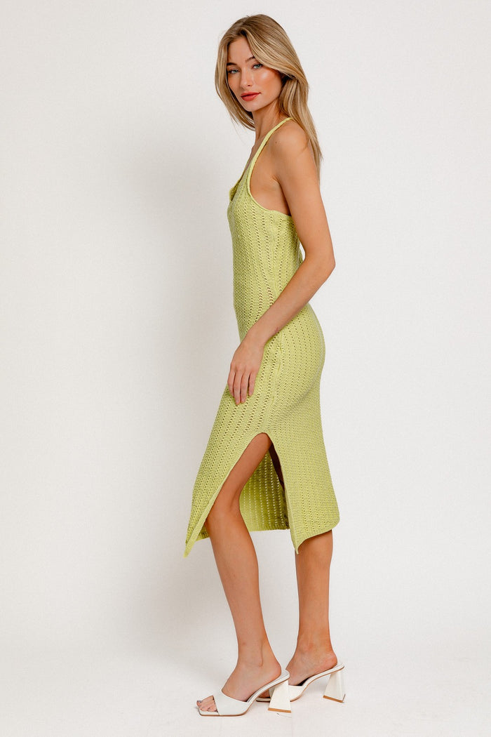 woman wearing a light green knitted midi dress with side slits and spaghetti straps