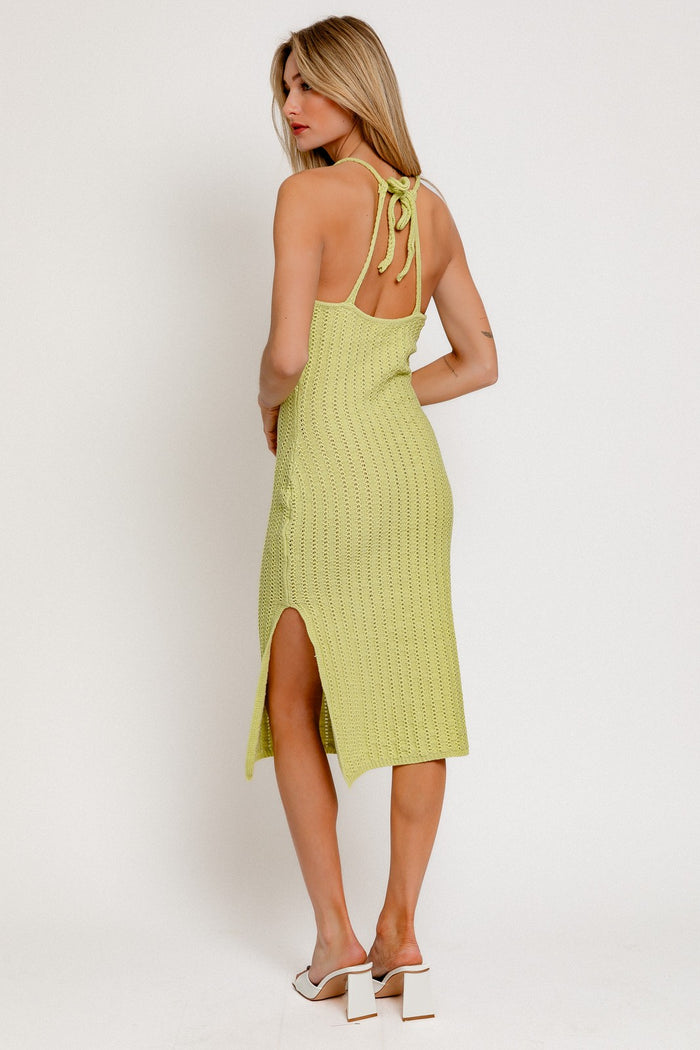 woman wearing a light green knitted midi dress with back ties and a side slit