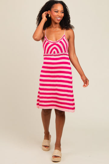 woman wearing a pink and white striped crochet dress with a fitted bodice and flared skirt, smiling and walking