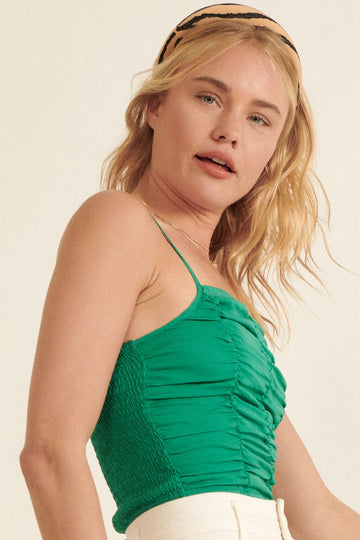 woman wearing a green smocked camisole top with thin straps and wavy blonde hair, styled with a headband