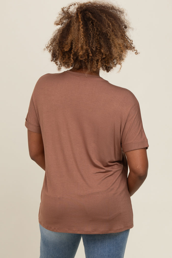 woman wearing a brown short sleeve top with rolled cuffs, showing the back view and styled with blue jeans