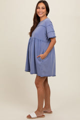 woman wearing a blue maternity dress with short sleeves, pockets, and frayed hem, showing her baby bump