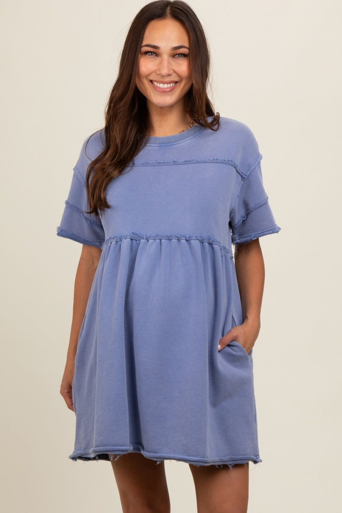 woman wearing a blue maternity dress with short sleeves and gathered waist, featuring frayed edges and pockets
