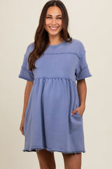 woman wearing a blue maternity dress with short sleeves and gathered waist, featuring frayed edges and pockets