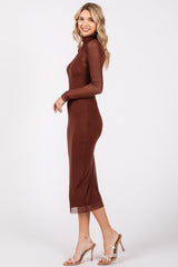 woman wearing a chocolate brown long sleeve fitted midi dress with a mock neck and transparent hem, standing sideways