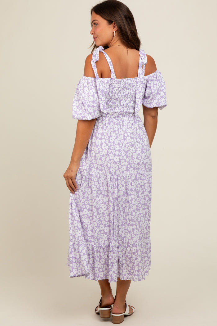woman wearing a purple floral off-shoulder maternity maxi dress with puff sleeves and a smocked bodice, showing her baby bump