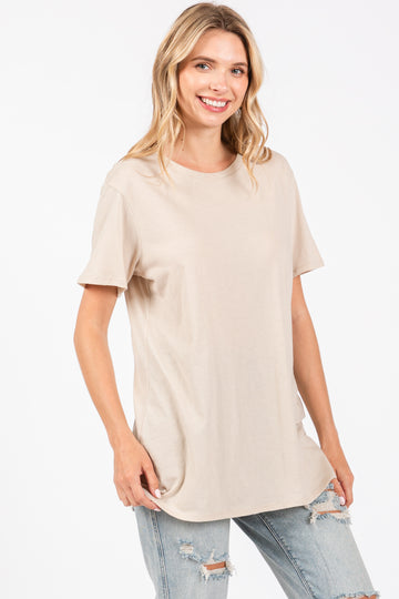 woman wearing a beige short sleeve t-shirt and light blue distressed jeans