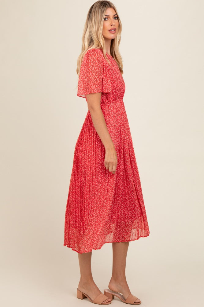 woman wearing a red floral midi dress with short sleeves and a pleated skirt, posed in profile