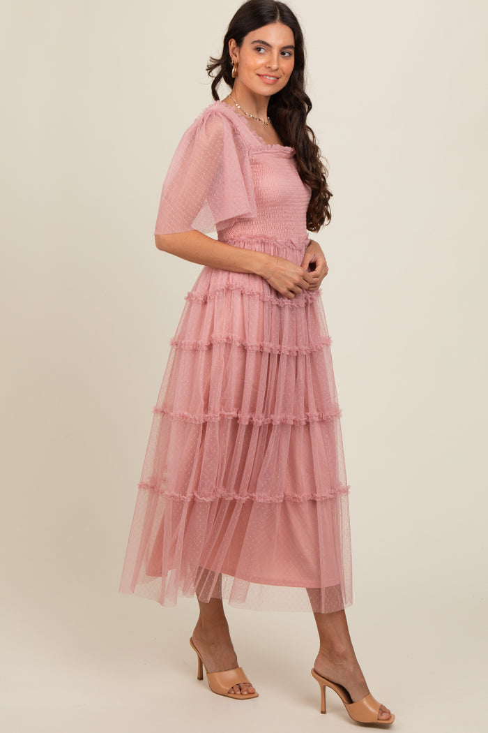 woman wearing a light pink tiered midi dress with puff sleeves and ruffle details, standing in profile