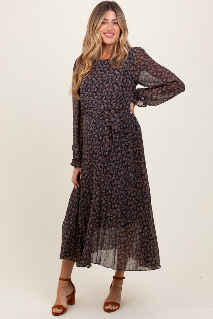 woman wearing a navy blue floral long sleeve maternity dress with a tie waist and flowy skirt