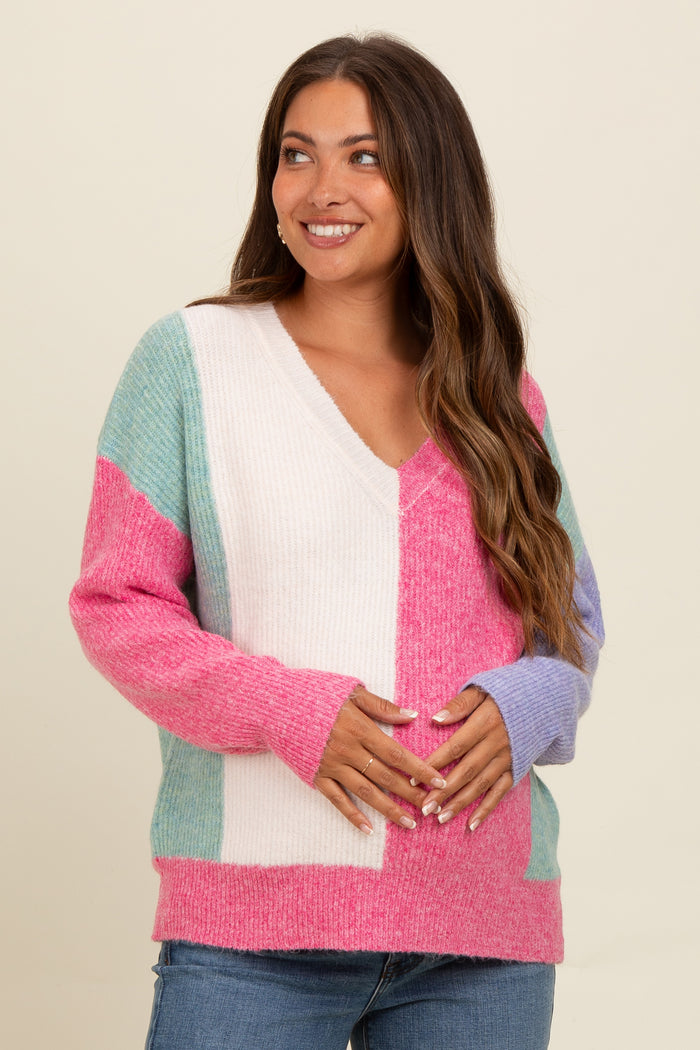 woman wearing a colorful maternity sweater with a v-neck and holding her baby bump