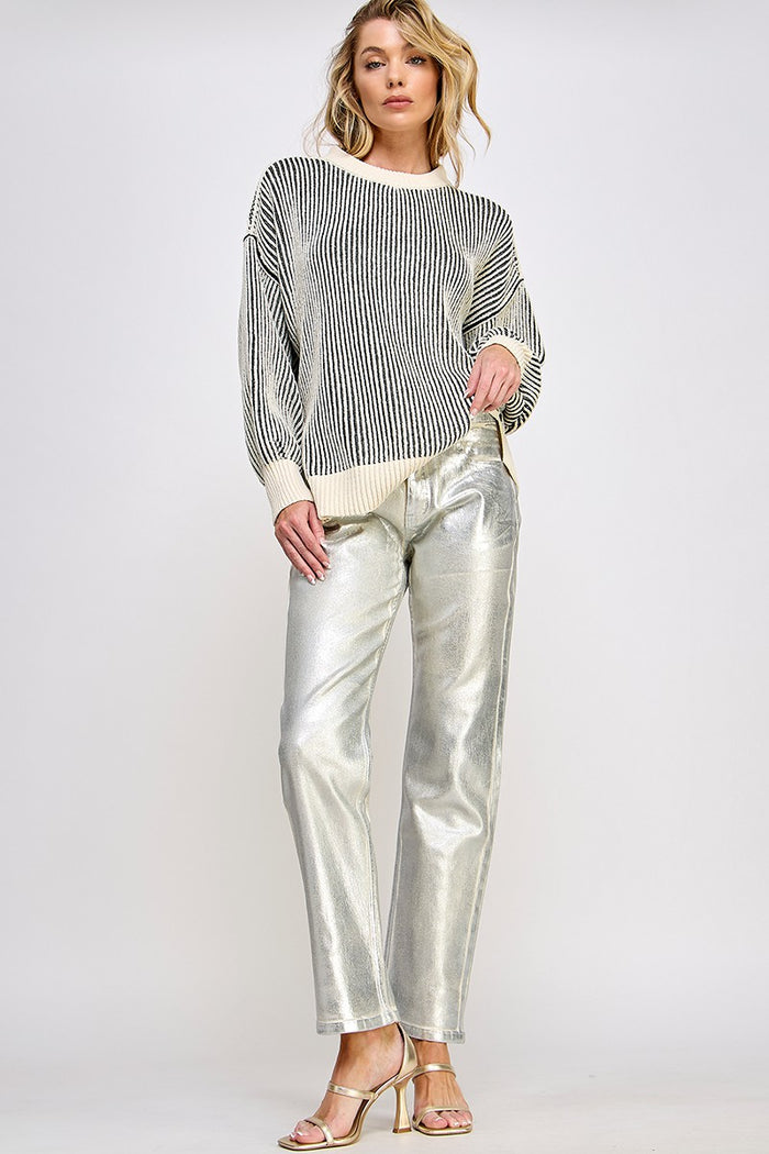 woman wearing a striped oversized sweater and shiny silver wide-leg pants with strappy heels