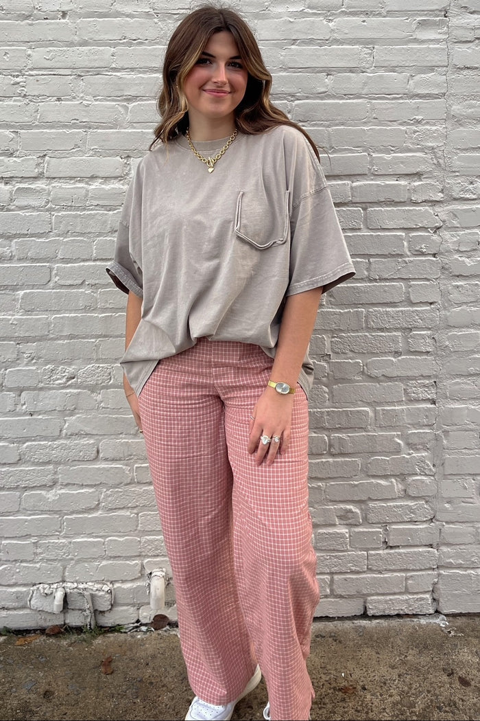 woman wearing an oversized gray t-shirt with a pocket and pink checkered wide-leg pants