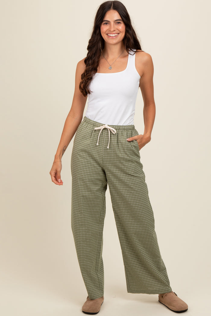 woman wearing a white tank top and green checkered wide-leg pants with a drawstring waist
