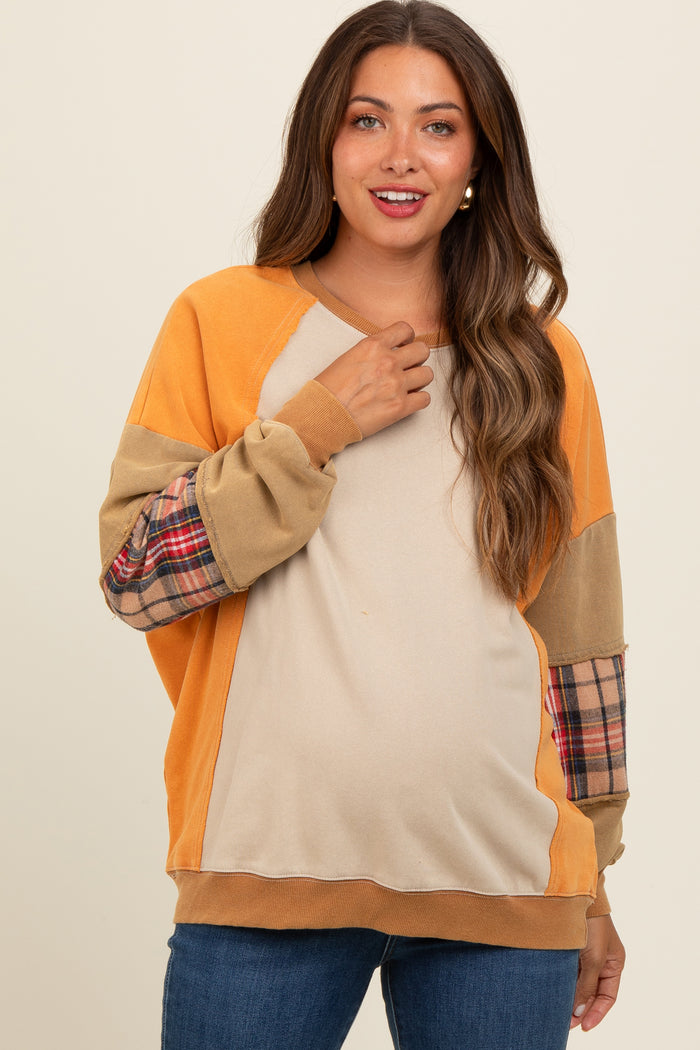 woman wearing an orange and beige long sleeve maternity sweatshirt with plaid detail and a visible baby bump