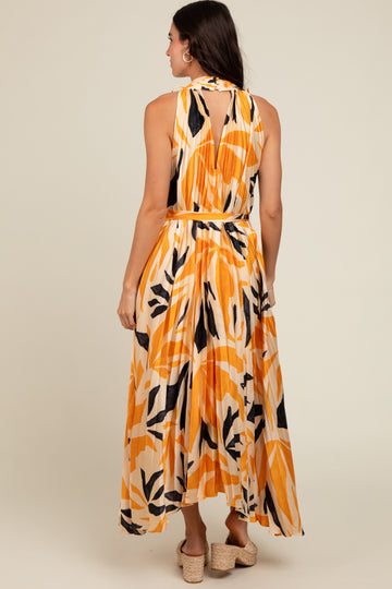 woman wearing a colorful floral maxi dress with an open back and tied waist, standing with her back to the camera