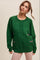 woman wearing a green cable knit sweater with contrasting pink detailing on the front