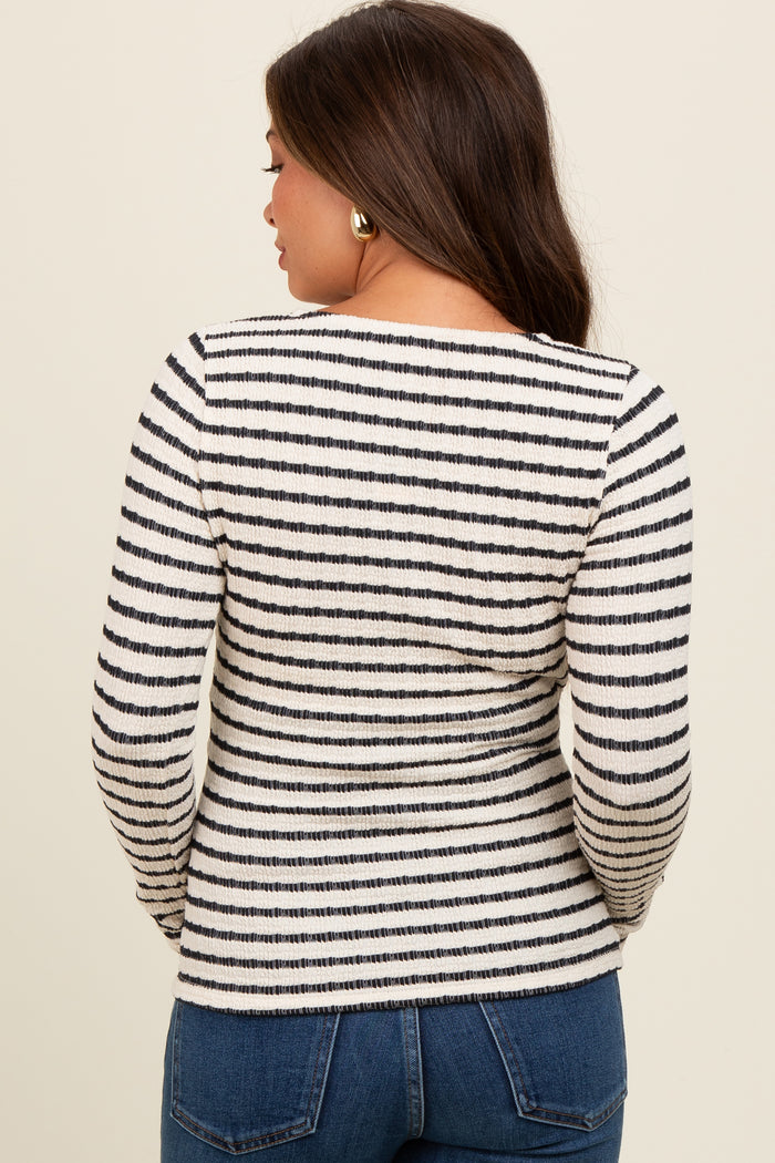 woman wearing a black and white striped long sleeve maternity top, seen from the back, paired with blue jeans