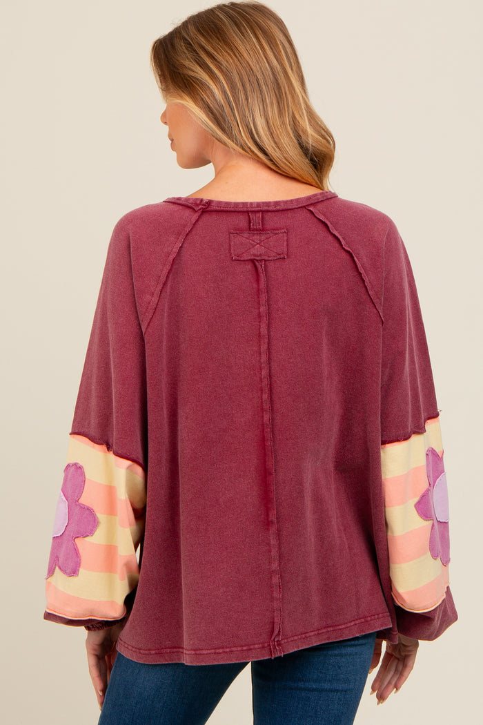 woman wearing a maroon maternity top with floral patterned sleeves and a relaxed fit, showing her back