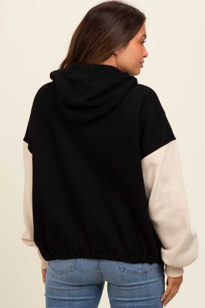 woman wearing a black and cream color block maternity hoodie with a relaxed fit and pullover style