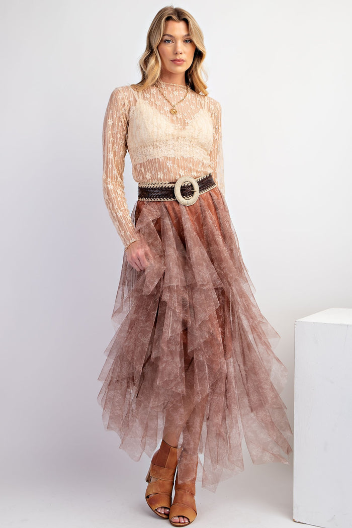 woman wearing a sheer long sleeve top with a beige bralette and a tiered brown tulle maxi skirt, accessorized with a statement belt