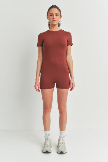 woman wearing a rust short-sleeve bodysuit with a fitted style and standing in neutral footwear