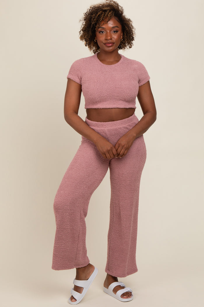 woman wearing a pink knit two-piece set with a cropped top and wide-leg pants, standing in white slide sandals