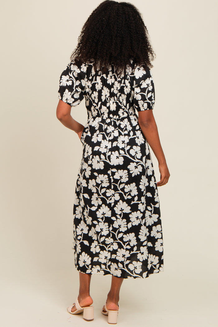 woman wearing a black and white floral midi dress with a smocked back detail and short puff sleeves