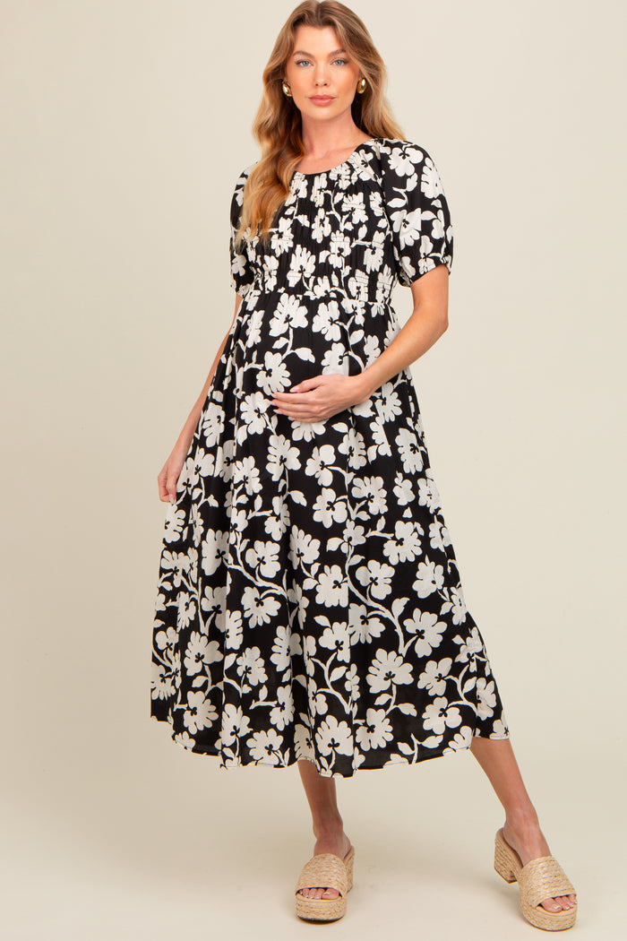 woman wearing a black and white floral maternity dress with a smocked bodice and a baby bump visible