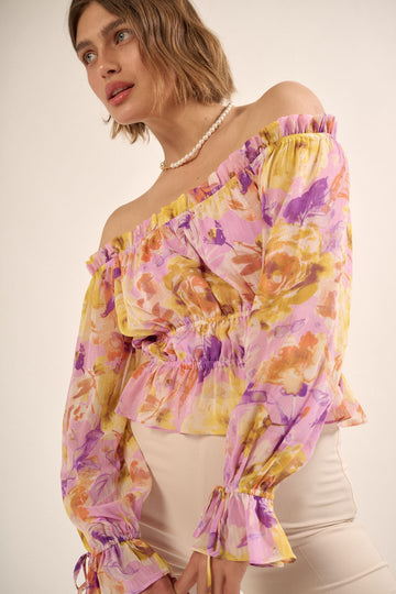 woman wearing a purple floral off-the-shoulder peplum top with ruffled sleeves and a cinched waist