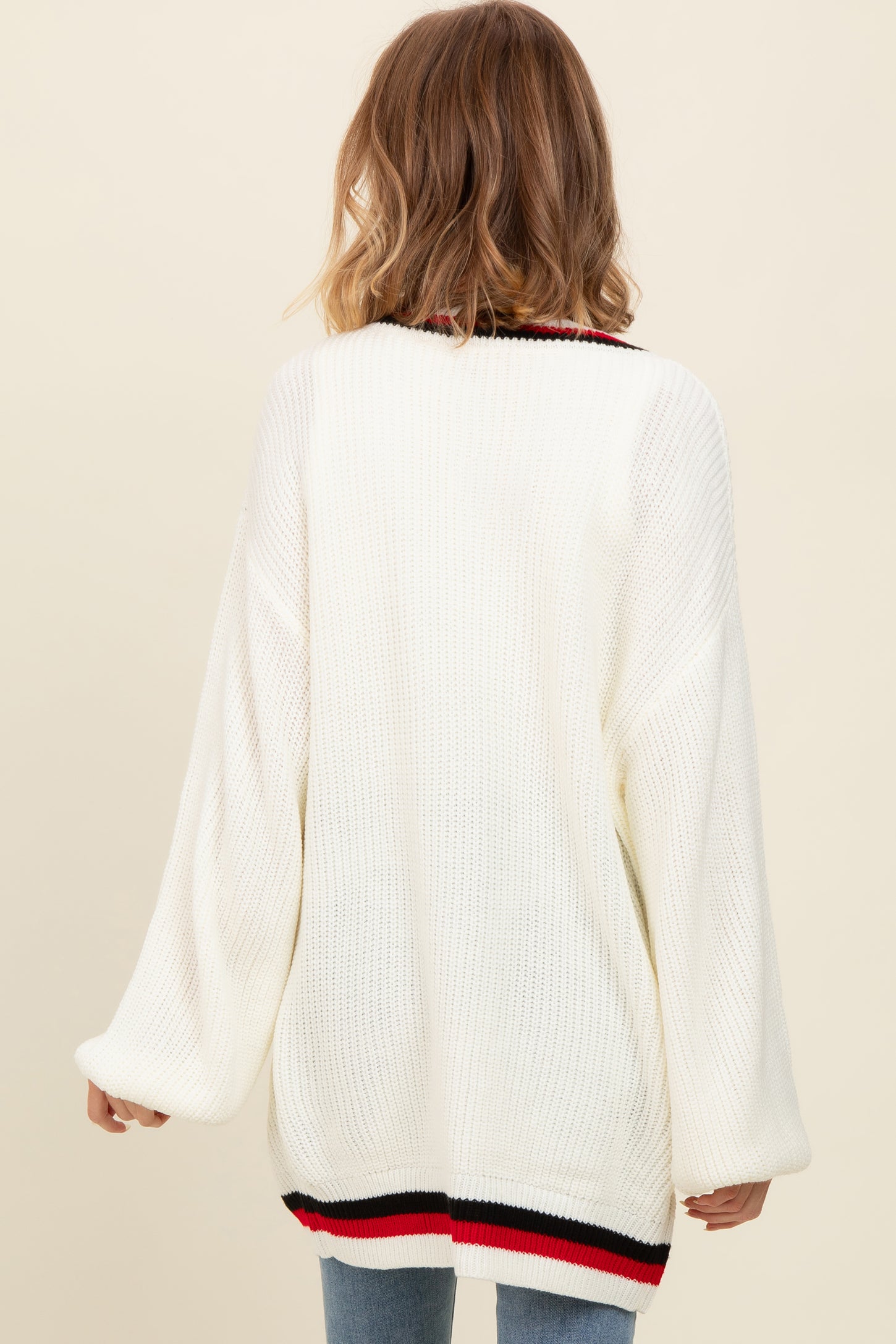 woman wearing an oversized white knitted sweater with a striped hem and long sleeves