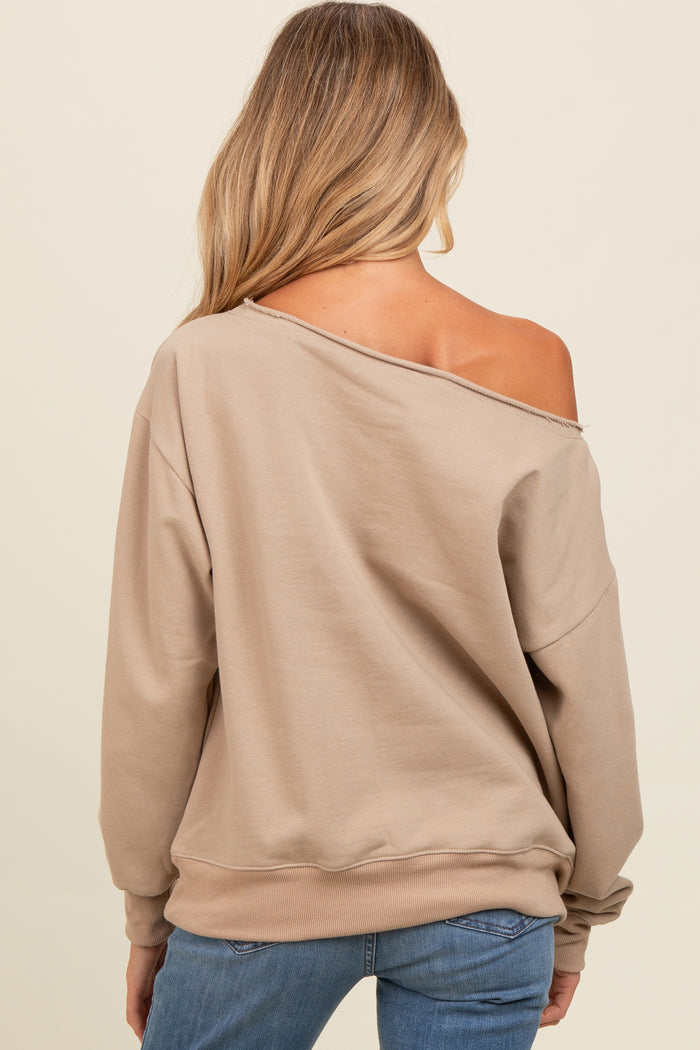 woman wearing a beige off-shoulder maternity sweatshirt styled casually with long sleeves and relaxed fit