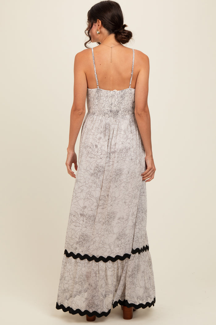 woman wearing a floral print maxi dress with a smocked back and black trim along the hem