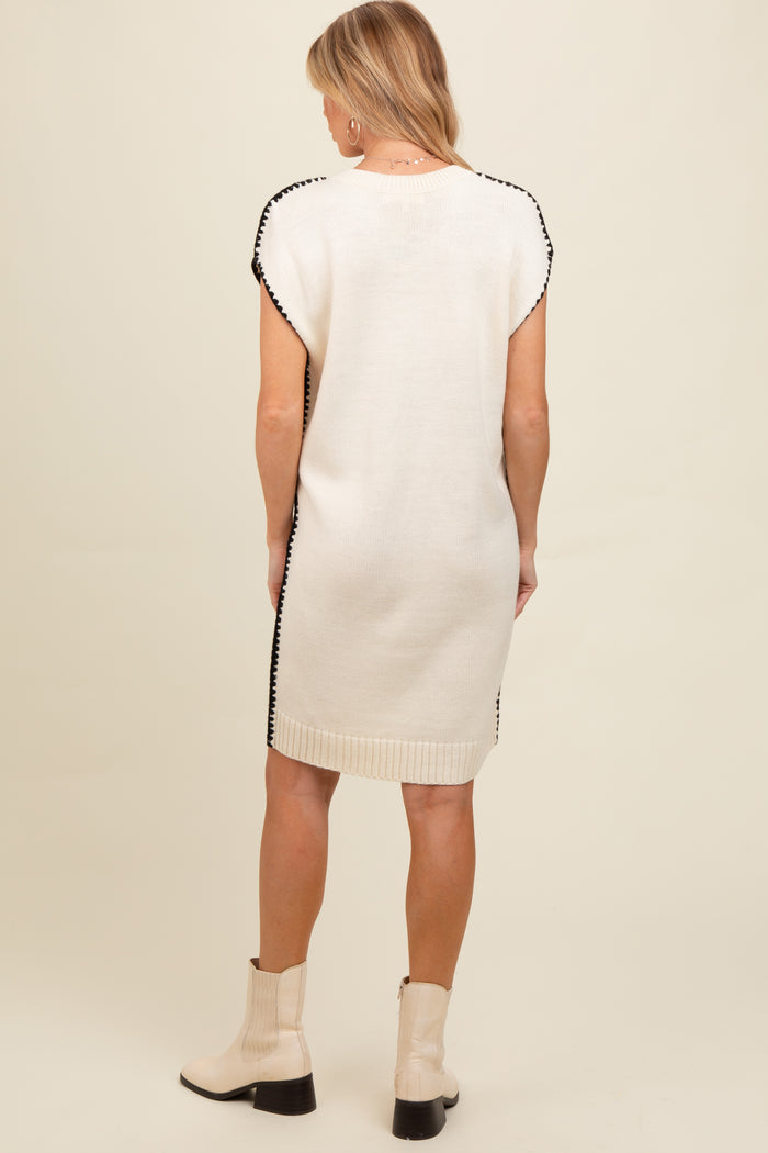 woman wearing a cream-colored maternity dress with black trim and short sleeves, viewed from the back