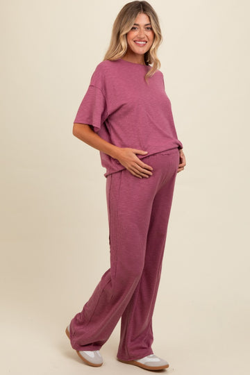 woman wearing a mauve ribbed maternity loungewear set with a relaxed fit and holding her baby bump