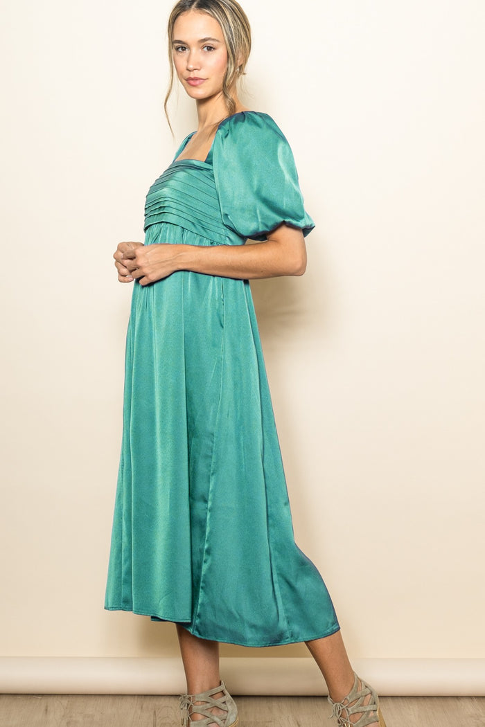 woman wearing a teal puff sleeve midi dress with a square neckline and pleated bodice