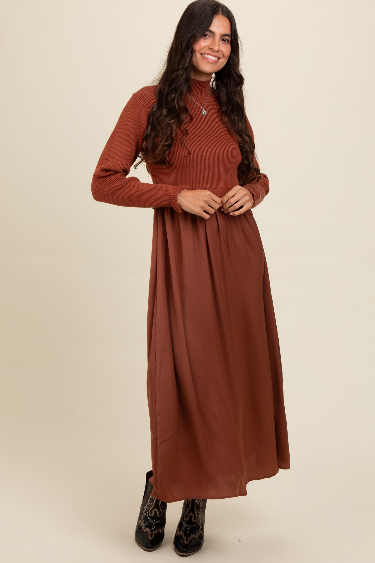 woman wearing a rust ribbed long sleeve knit top with a flowy brown maxi skirt
