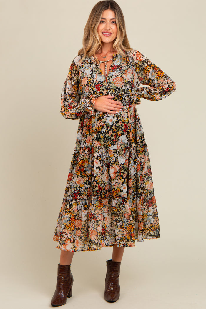 woman wearing a floral printed maternity dress with puffed sleeves and a tie neckline, highlighting her baby bump