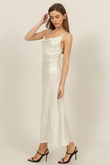 woman wearing a white satin evening gown with a cowl neckline and side ruching, paired with black strappy heels