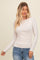 woman wearing a light beige long sleeve top with gathered detail and a round neckline, paired with blue jeans