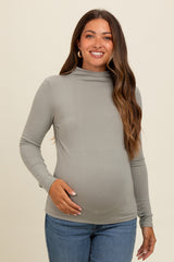 woman wearing a light grey long sleeve maternity top and showing her baby bump