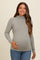 woman wearing a light grey long sleeve maternity top and showing her baby bump