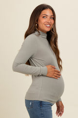 woman wearing a light gray long sleeve maternity top and holding her baby bump