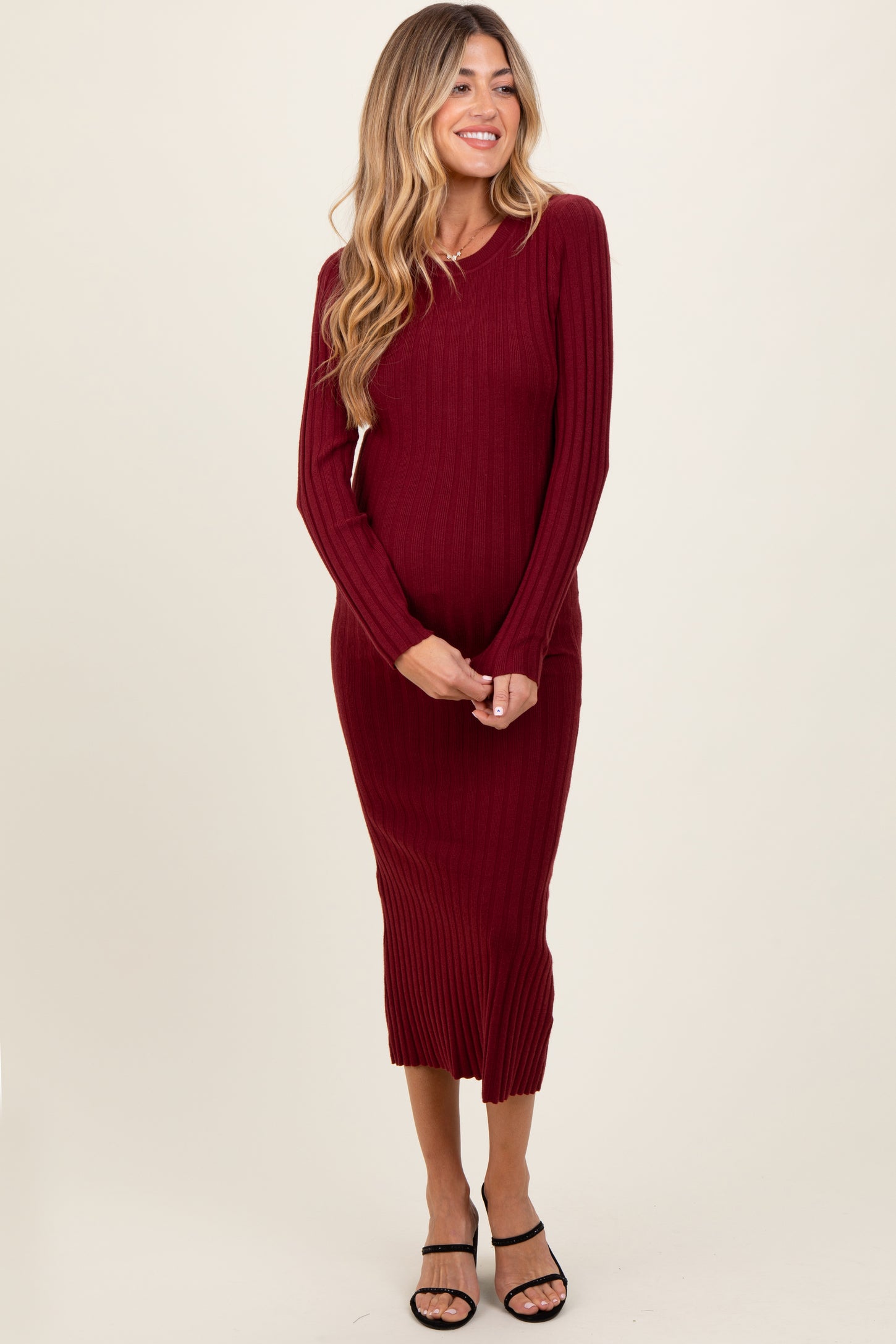woman wearing a burgundy ribbed maternity dress with long sleeves and a fitted silhouette, showing her baby bump