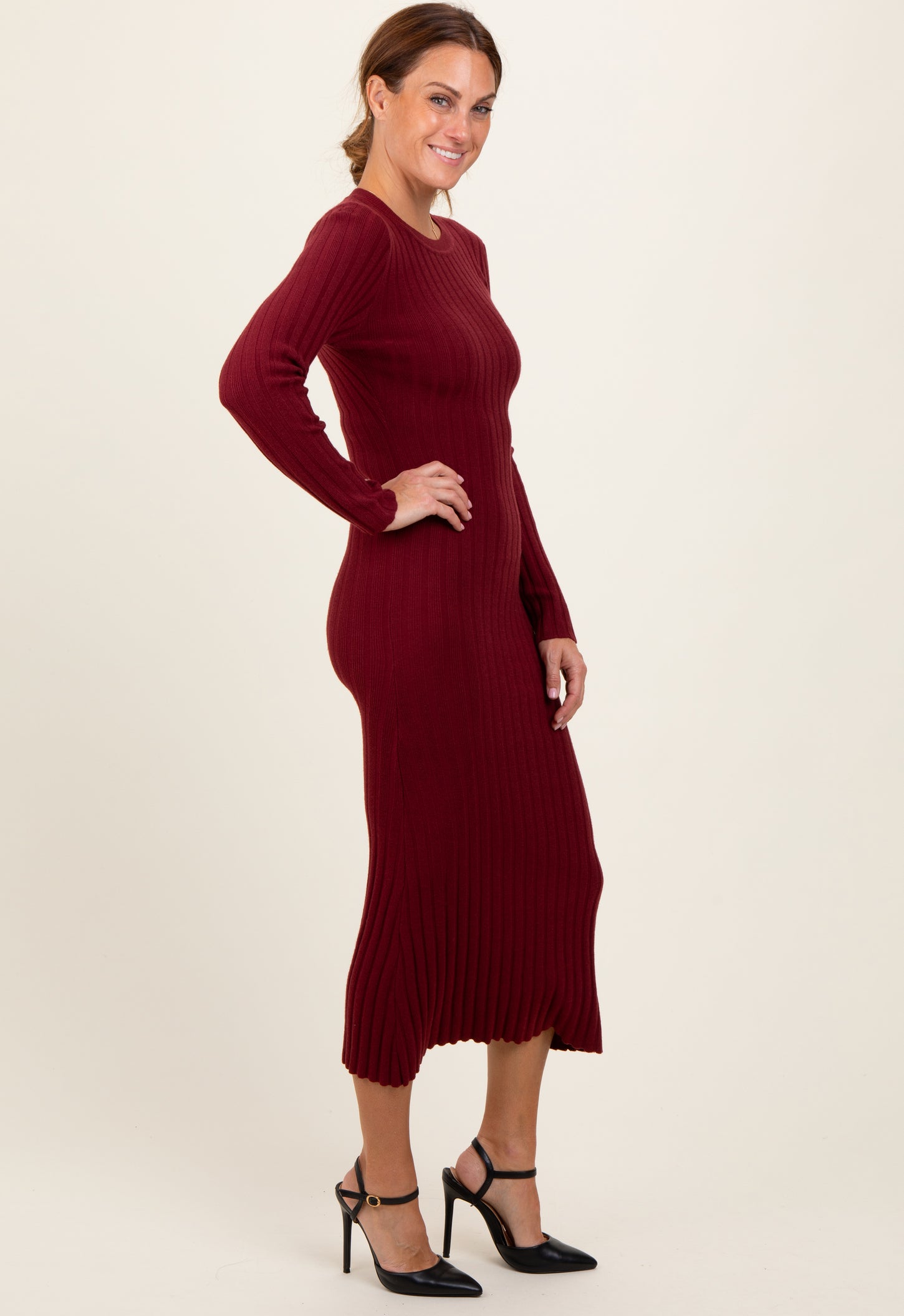woman wearing a burgundy ribbed long sleeve midi dress with a fitted silhouette and side slit