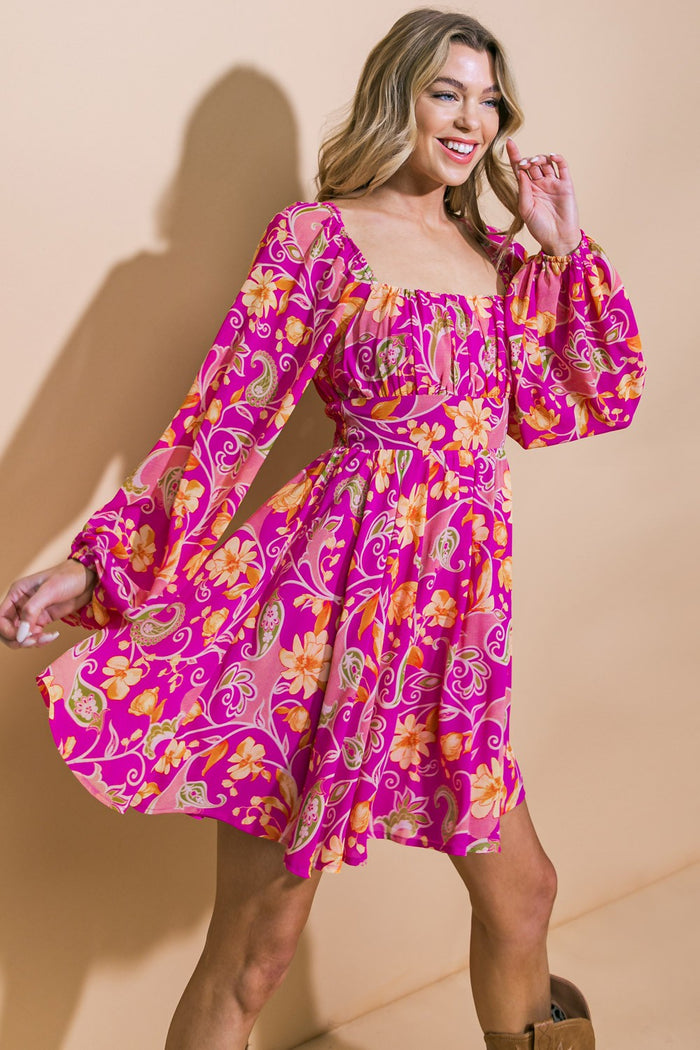 woman wearing a bright pink floral print mini dress with puff sleeves and a square neckline